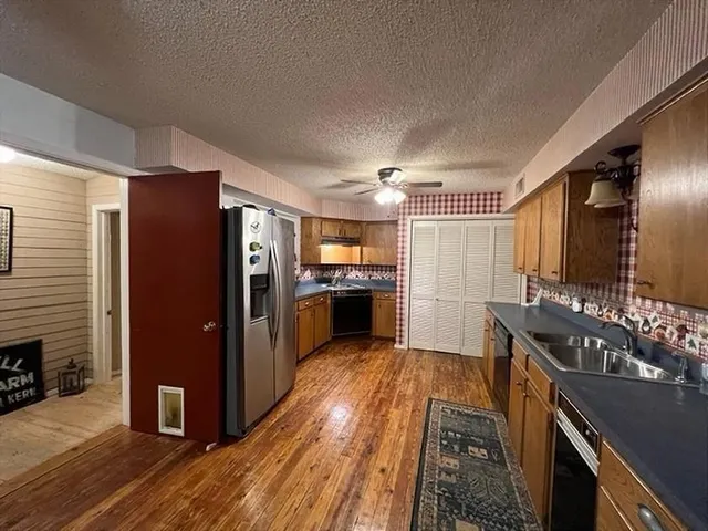 a living room with furniture a bookshelf and kitchen view