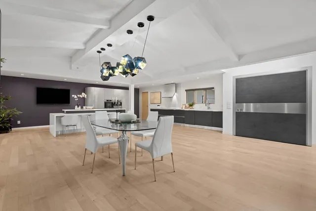 a dining room with wooden floor a chandelier a wooden table and chairs