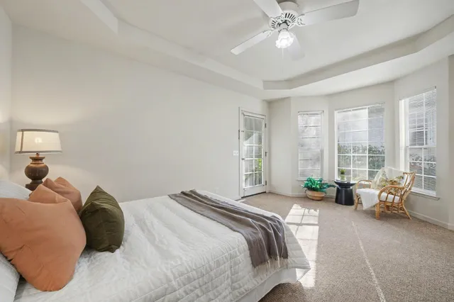 a bedroom with a bed couches and large windows