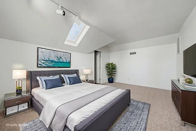 a bedroom with a bed a mirror on dresser and a couch