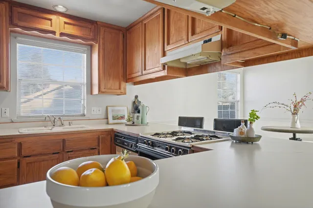 a kitchen with stainless steel appliances granite countertop a sink a stove and a wooden floors
