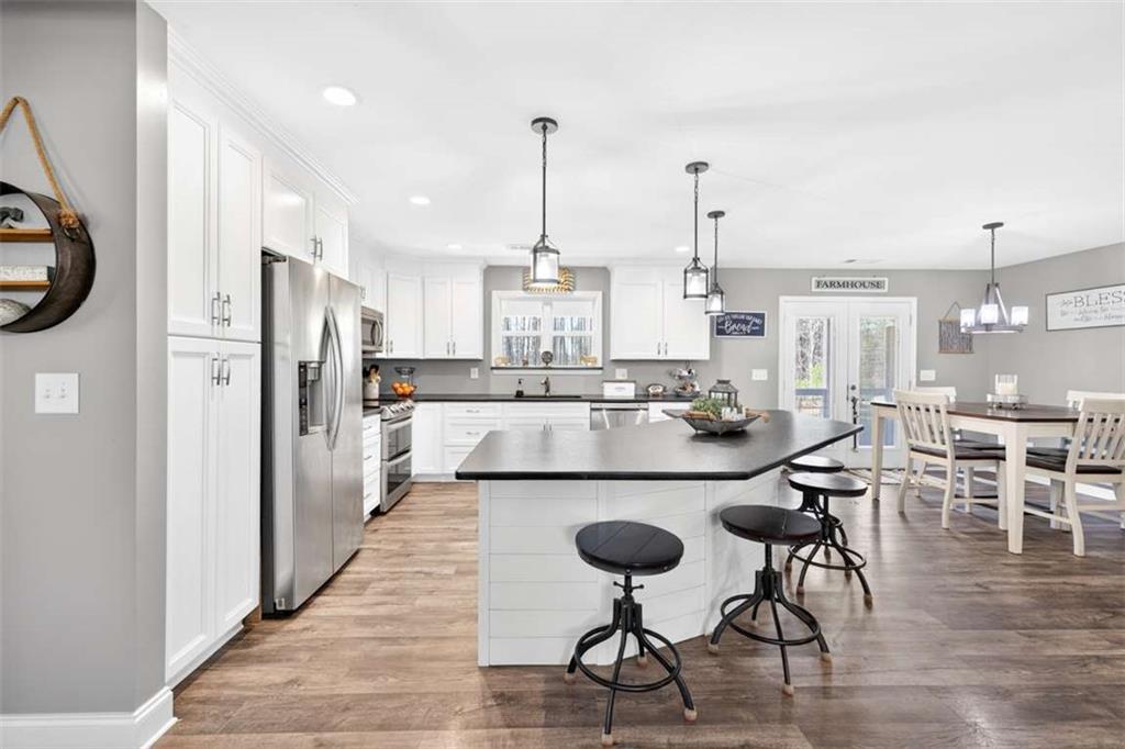 2361 County Line Road Mansfield, GA 30055 - Photo 17 of 57 a kitchen with stainless steel appliances kitchen island granite countertop a dining table chairs and white cabinets