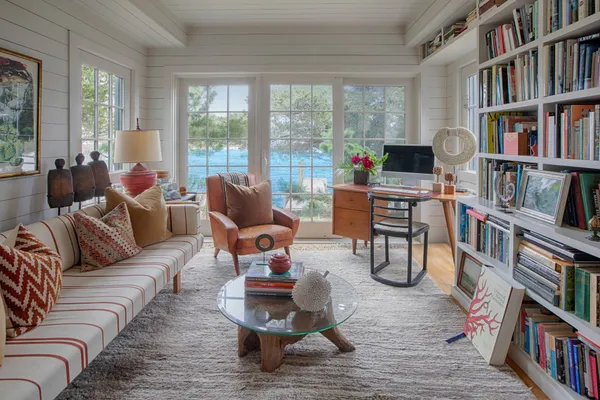 a living room with furniture lots of books and a large window