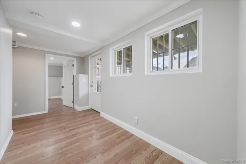a view of an empty room with wooden floor and windows