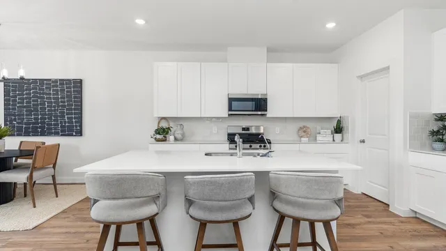 a kitchen with stainless steel appliances a sink a stove a table and chairs