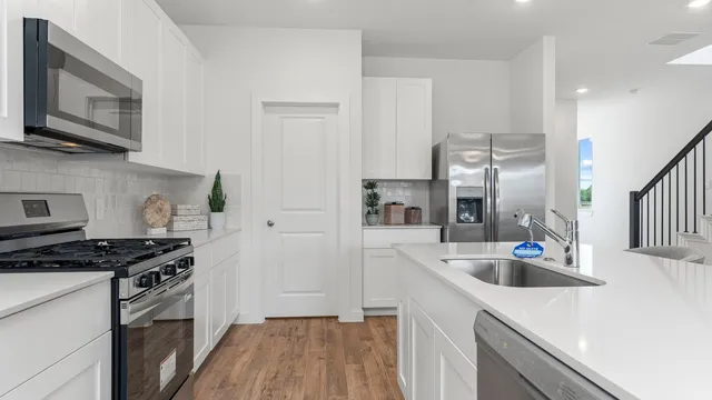 a kitchen with stainless steel appliances a sink a stove a microwave a refrigerator and cabinets