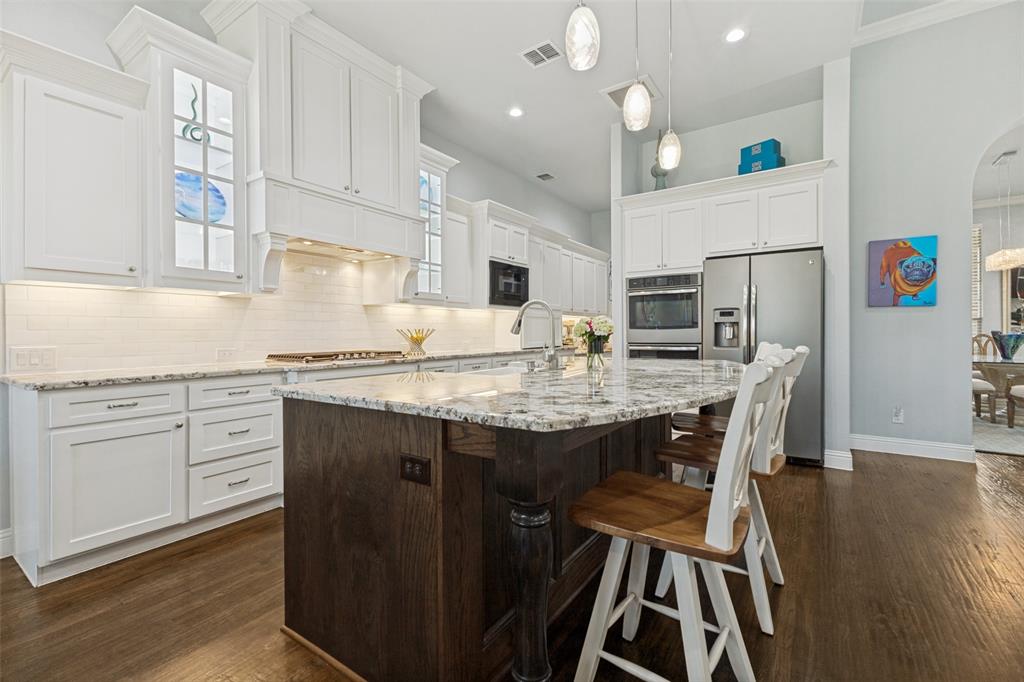 506 Life Spring Drive Rockwall, TX 75087 - Photo 12 of 36 a kitchen with kitchen island granite countertop a sink cabinets and wooden floor