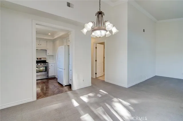 a view of a livingroom with a chandelier fan and kitchen view