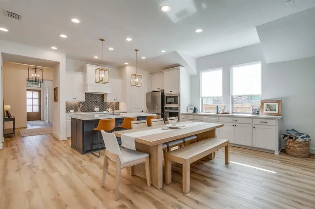a kitchen with stainless steel appliances granite countertop a table chairs sink refrigerator and cabinets
