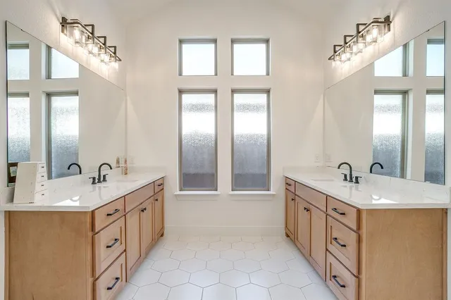 a spacious bathroom with a double vanity sink a mirror a bathtub and next to a window