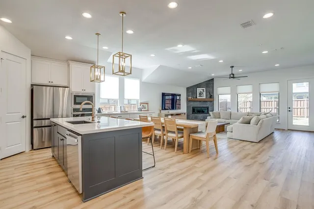 a kitchen with stainless steel appliances granite countertop a refrigerator a stove top oven a dining table and chairs with wooden floor