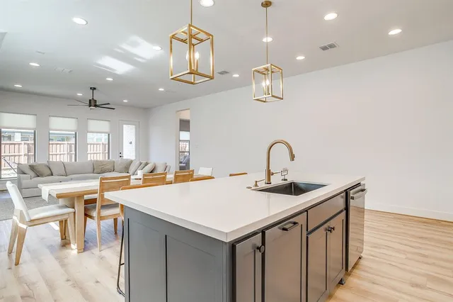 a kitchen that has a lot of cabinets a sink and wooden floor