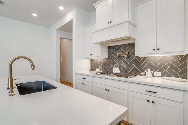 a kitchen with white cabinets and sink