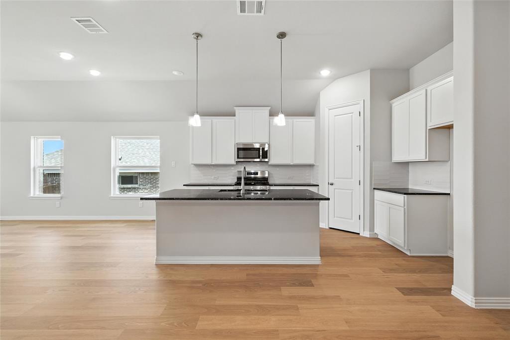 530 Red Barn Drive Van Alstyne, TX 75495 - Photo 2 of 40 Kitchen with stainless steel microwave, dark countertops, backsplash, white cabinetry, and light wood-style floors