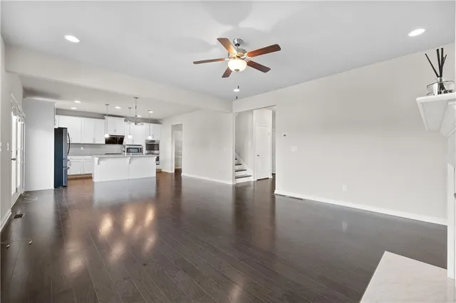 an empty room with wooden floor fireplace and windows