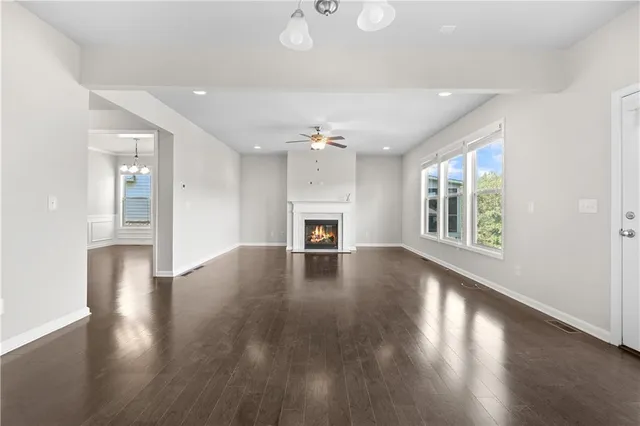an empty room with wooden floor fireplace and windows