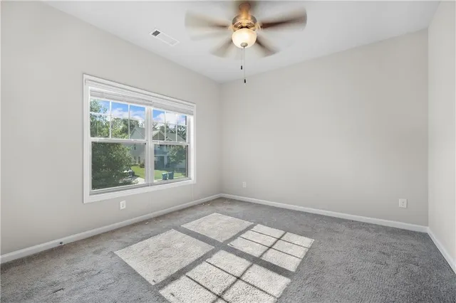 an empty room with windows and ceiling fan