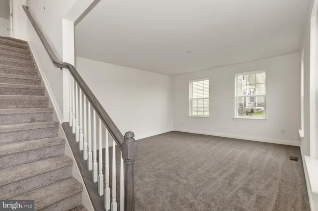 a view of an empty room with wooden floor and stairs