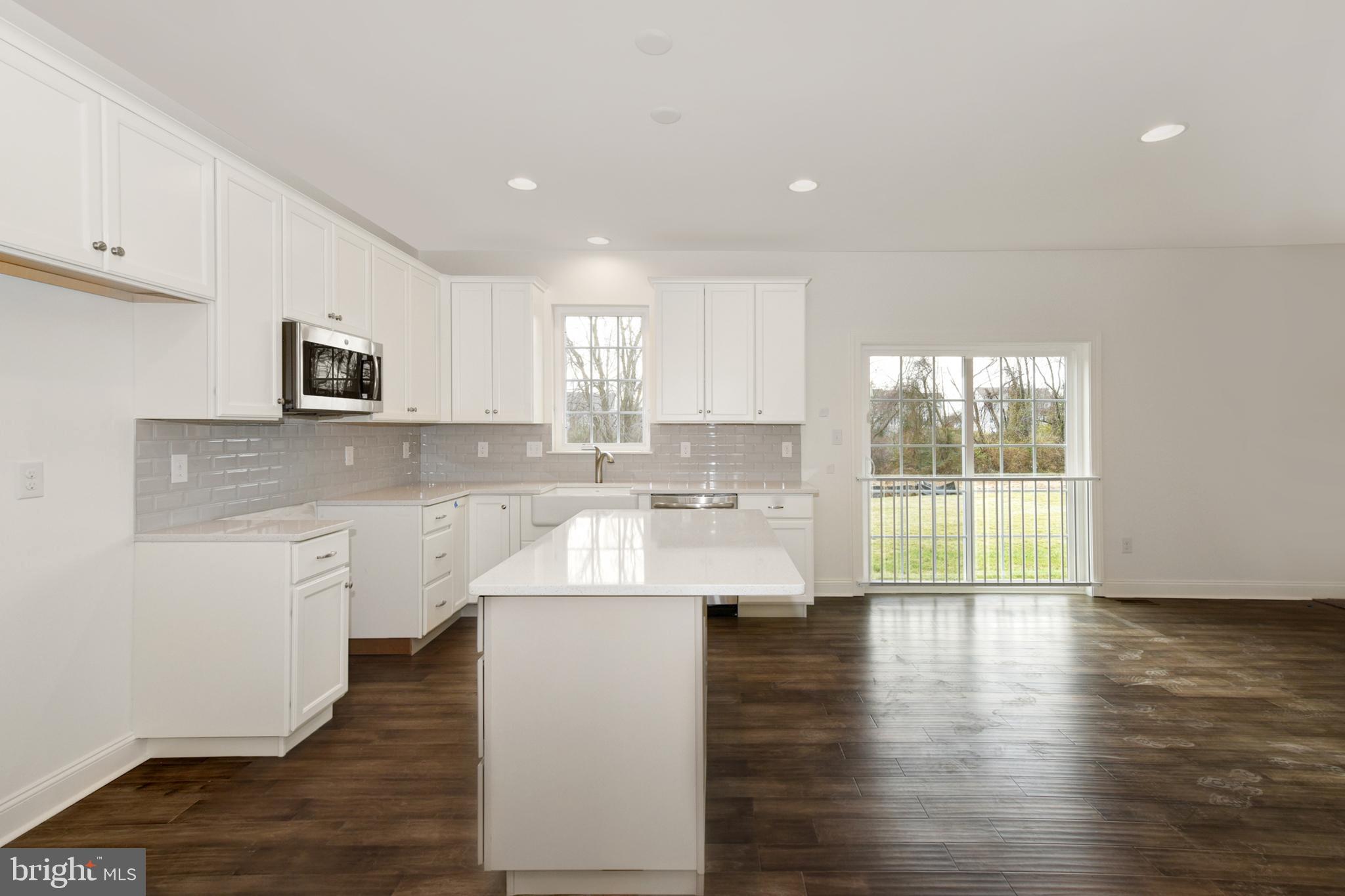 400 Rederick Lane, Unit 2 Middletown, DE 19709 - Photo 5 of 23 a large kitchen with stainless steel appliances granite countertop a stove a sink and white cabinets with wooden floor next to windows