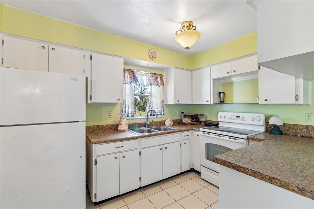2059 Waterfall Drive Spring Hill, FL 34608 - Photo 7 of 26 a kitchen with a sink dishwasher a refrigerator a stove and white cabinets with wooden floor