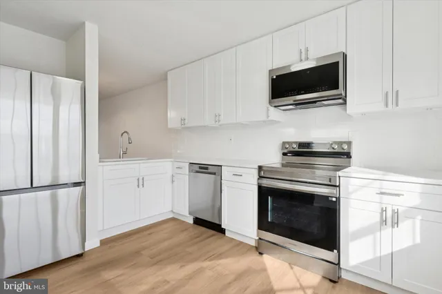 a kitchen with cabinets stainless steel appliances and wooden floor