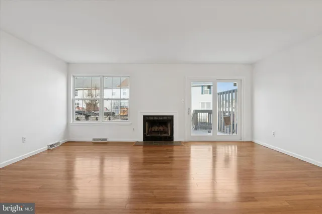 a view of empty room with wooden floor and fireplace