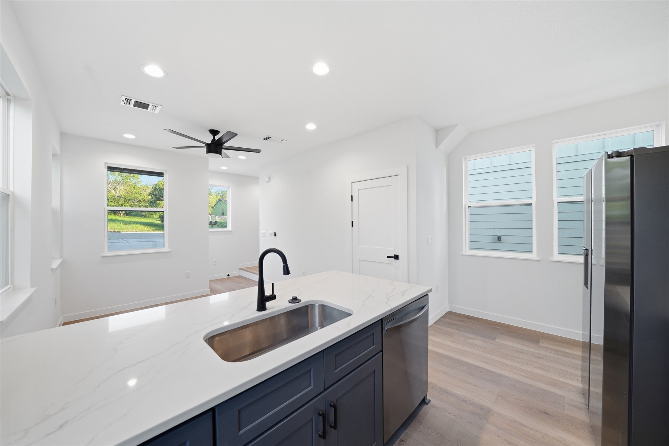 2212 Yellow Jacket Lane, Unit 2 Austin, TX 78741 - Photo 5 of 25 Open-concept kitchen featuring a large island with an undermount stainless steel sink, a matte black faucet, and a dishwasher
