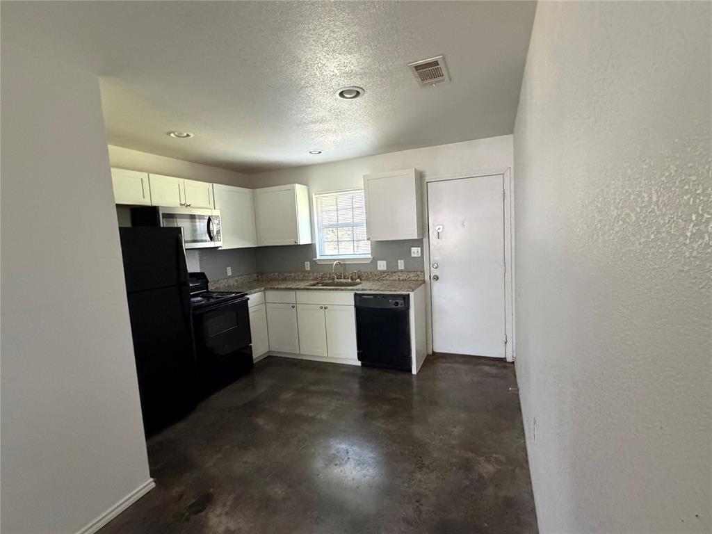 712 Seven Oaks Road, Unit 712 Bonham, TX 75418 - Photo 4 of 14 a kitchen with a sink a refrigerator a window and cabinets
