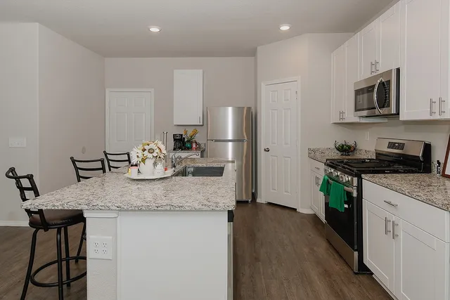 a kitchen with stainless steel appliances granite countertop a kitchen island hardwood floor sink and stove