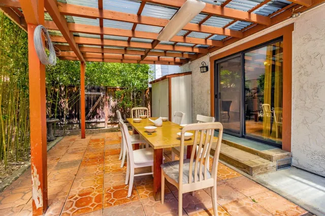 a view of a patio with table and chairs potted plants and large tree