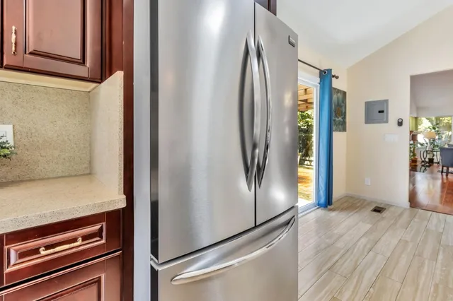 a kitchen with stainless steel appliances granite countertop a stove a sink dishwasher a refrigerator a stove and white cabinets with wooden floor