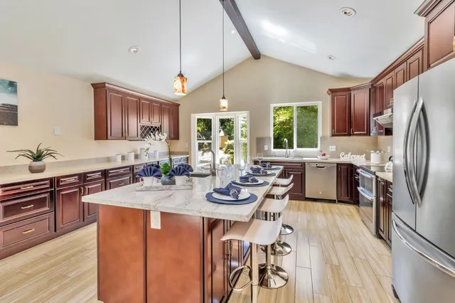 a kitchen with kitchen island granite countertop a sink appliances and cabinets