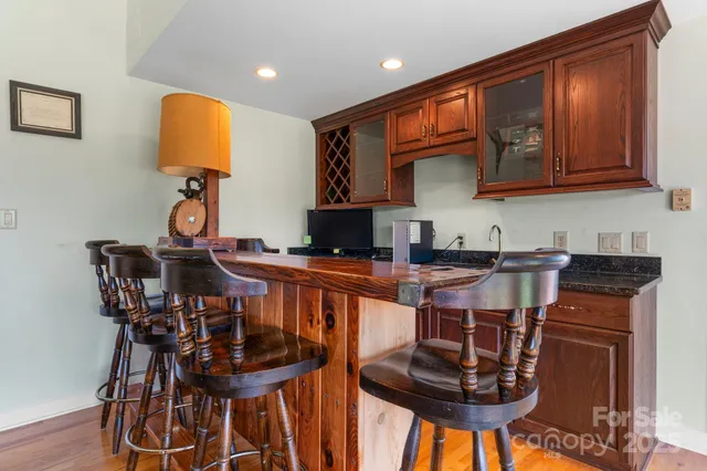 a kitchen with stainless steel appliances granite countertop a stove a refrigerator a sink a dining table and chairs with wooden floor