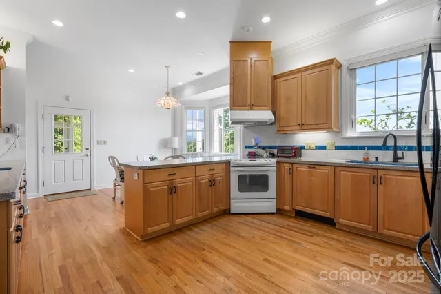 a kitchen with granite countertop a sink cabinets stainless steel appliances and window
