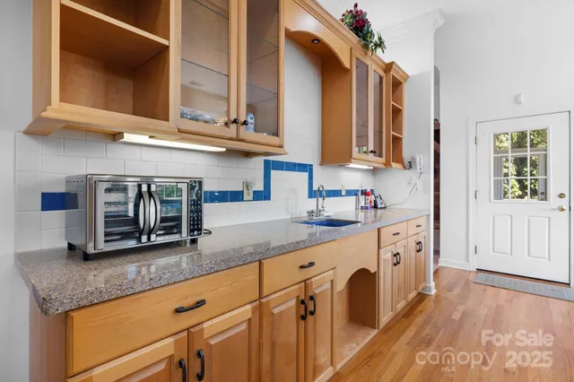 a kitchen with stainless steel appliances granite countertop a sink a stove and a microwave oven with white cabinets