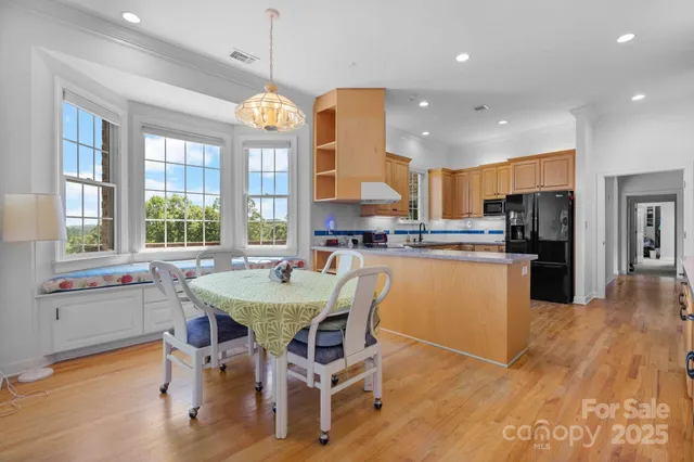 a kitchen with stainless steel appliances granite countertop a stove a refrigerator a kitchen island a dining table and chairs