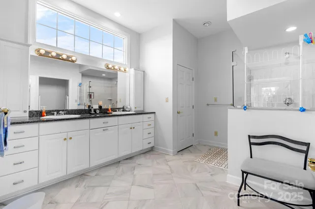 a spacious bathroom with a granite countertop sink a mirror and a bathtub