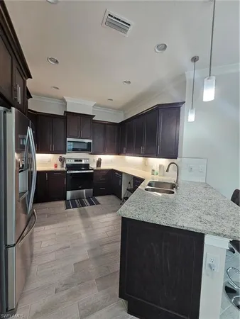 a kitchen with stainless steel appliances granite countertop a sink counter space cabinets and a refrigerator