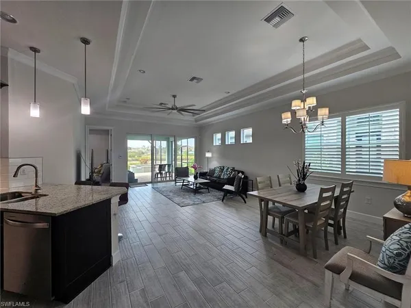 a view of a dining room and livingroom with furniture wooden floor a chandelier