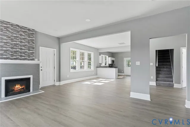 a view of an empty room with wooden floor fireplace and a window
