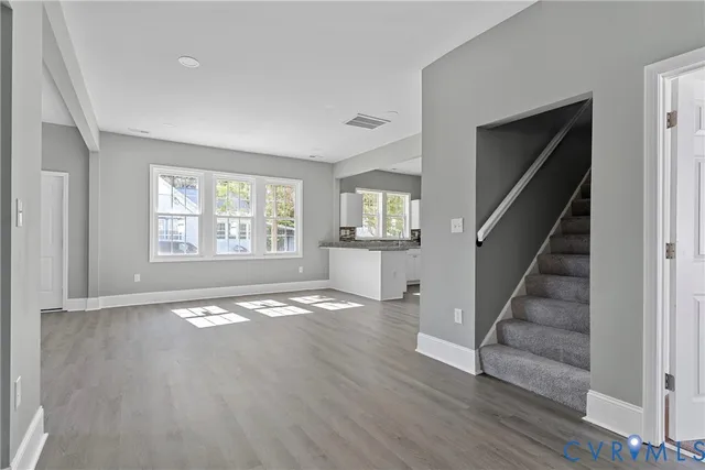 a view of an empty room with wooden floor and stairs