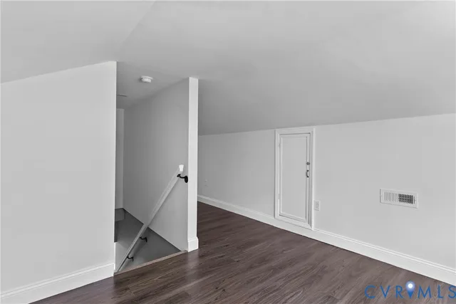 an empty room with wooden floor and entrance