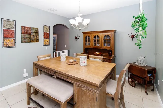 a dining room with wooden floor a chandelier fan a wooden table and chairs