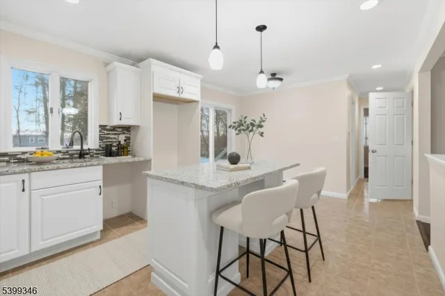 a kitchen with stainless steel appliances kitchen island granite countertop a dining table chairs and white cabinets