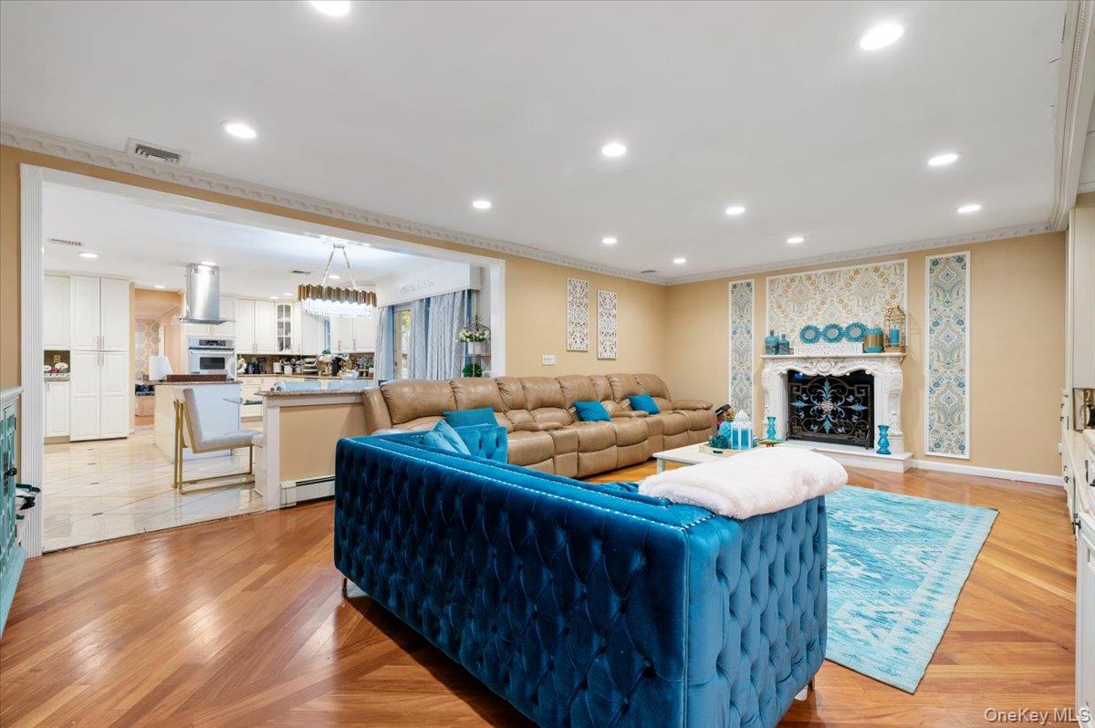 626 Caledonia Road Dix Hills, NY 11746 - Photo 12 of 50 Living area with recessed lighting, a fireplace with raised hearth, ornamental molding, a baseboard radiator, and light wood finished floors
