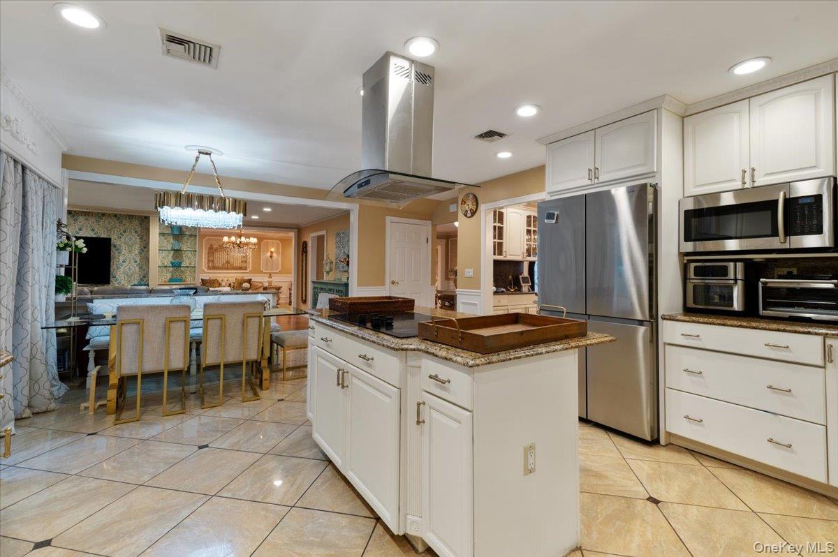 626 Caledonia Road Dix Hills, NY 11746 - Photo 18 of 50 Kitchen with white cabinetry, appliances with stainless steel finishes, recessed lighting, wallpapered walls, and island range hood