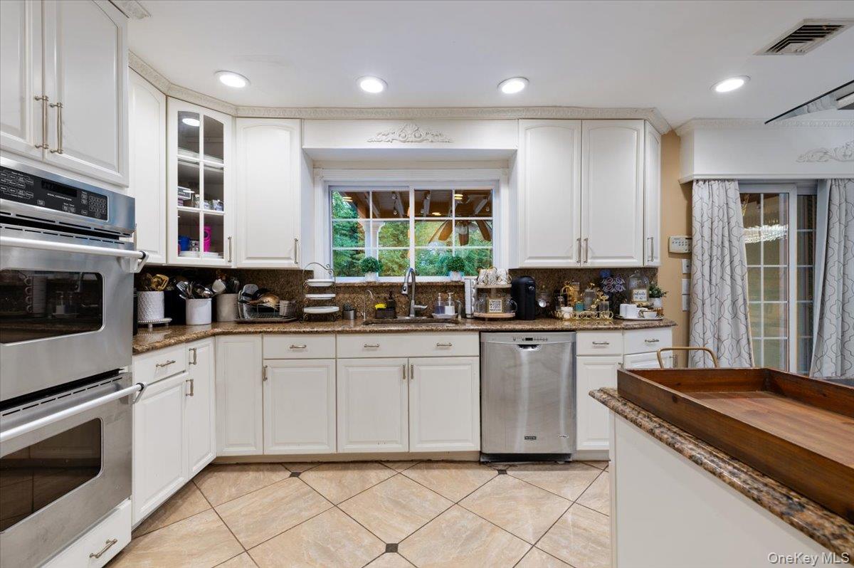 626 Caledonia Road Dix Hills, NY 11746 - Photo 19 of 50 Kitchen featuring stainless steel appliances, dark stone counters, white cabinets, backsplash, and recessed lighting