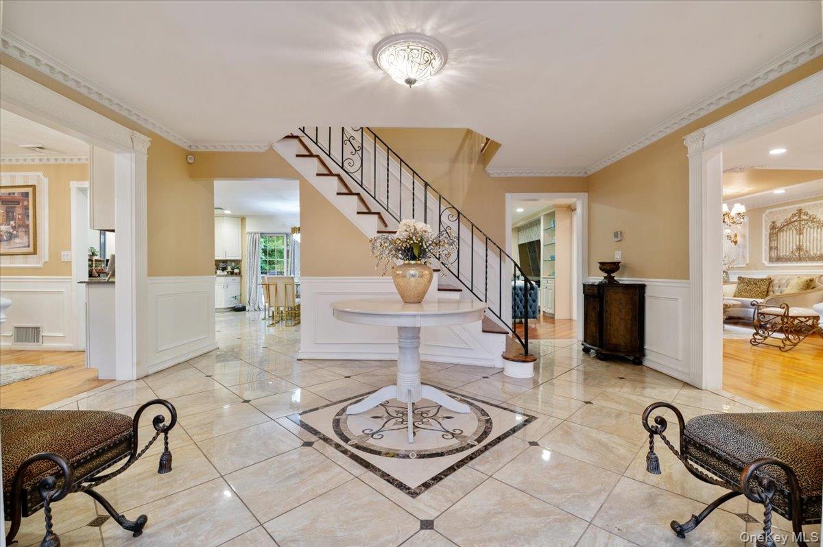 626 Caledonia Road Dix Hills, NY 11746 - Photo 4 of 50 Foyer with wainscoting, a decorative wall, a chandelier, stairway, and ornamental molding
