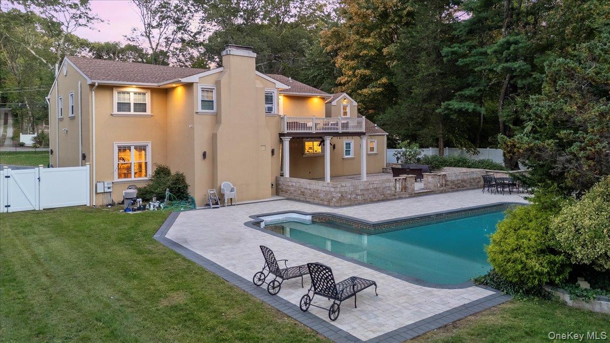 626 Caledonia Road Dix Hills, NY 11746 - Photo 44 of 50 Back of property at dusk with a patio, a gate, a fenced backyard, stucco siding, and a chimney