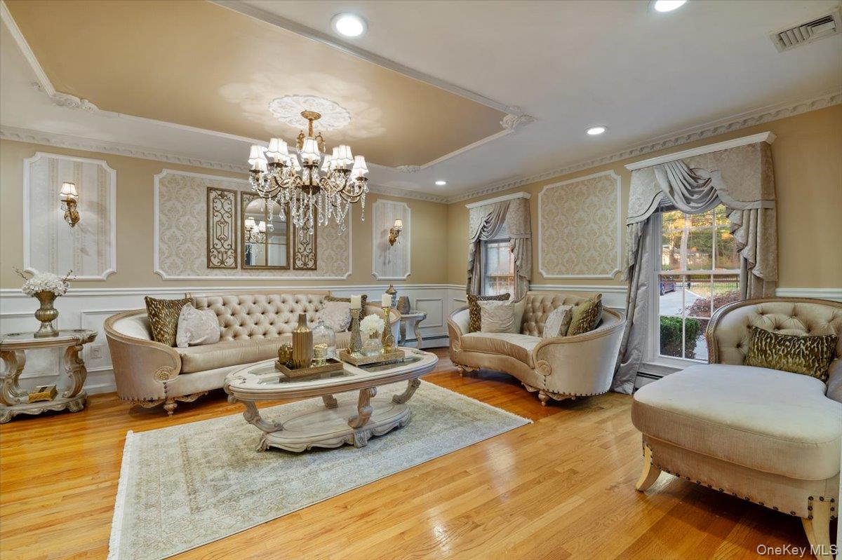 626 Caledonia Road Dix Hills, NY 11746 - Photo 6 of 50 Living room featuring a decorative wall, wood finished floors, recessed lighting, a chandelier, and a raised ceiling